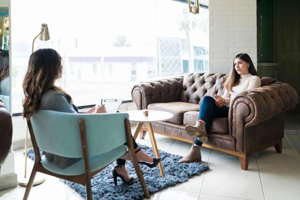 Woman sharing problems with female therapist while sitting on couch at office