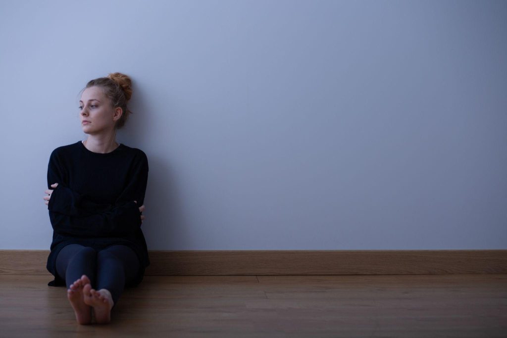 sad teenage girl suffering from loneliness, sitting alone on the floor